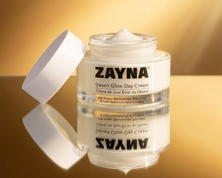 ZAYNA Desert Glow Day Cream in a white jar with open lid, featuring argan oil and hyaluronic acid on reflective base