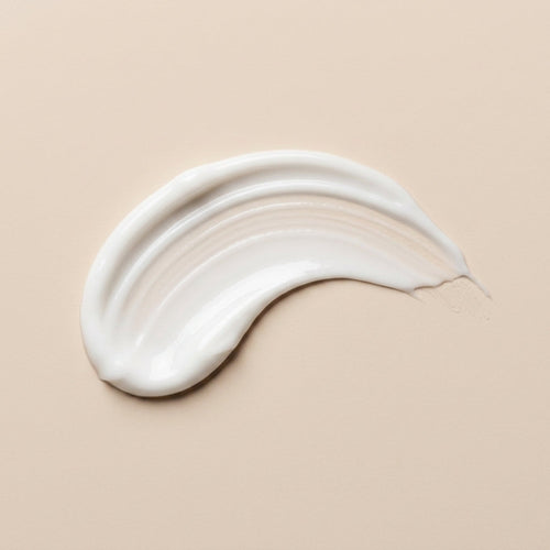 ZAYNA Desert Glow Day Cream white hydrating face moisturizer texture swatch on a beige background.